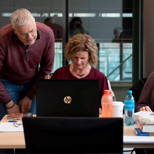 student van deeltijdopleiding Theologie legt wat uit aan een andere student