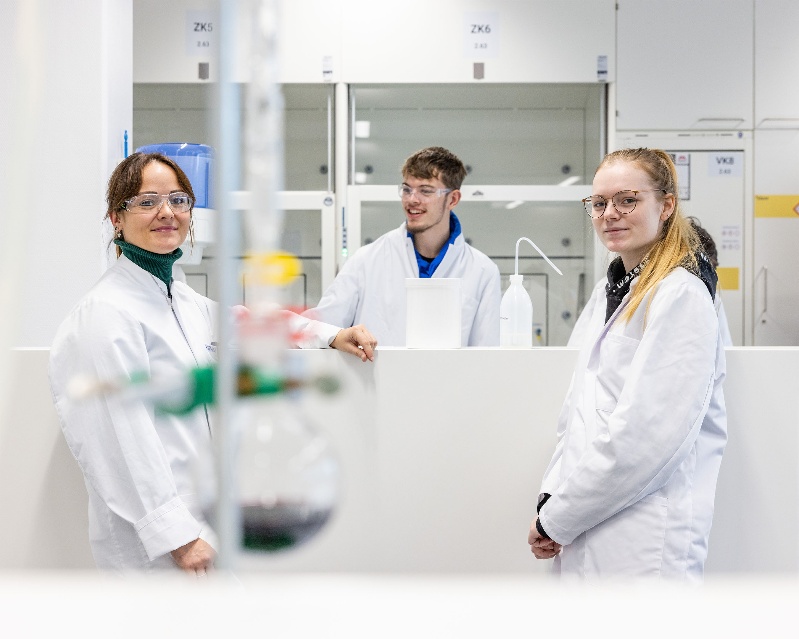 Three students in white lab coats