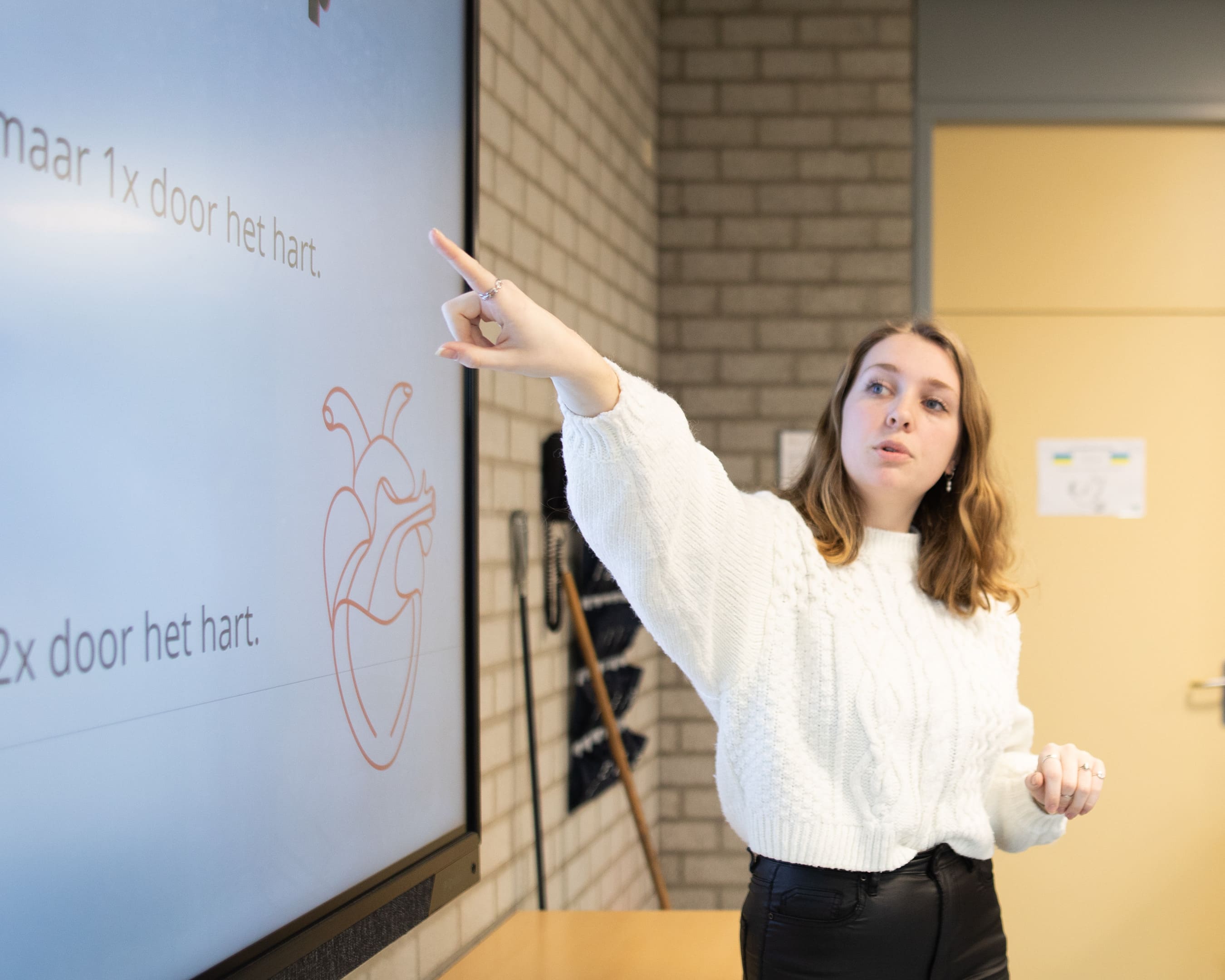 Een docent Leraar Gezondheidszorg en Welzijn geeft les voor een digitaal scherm