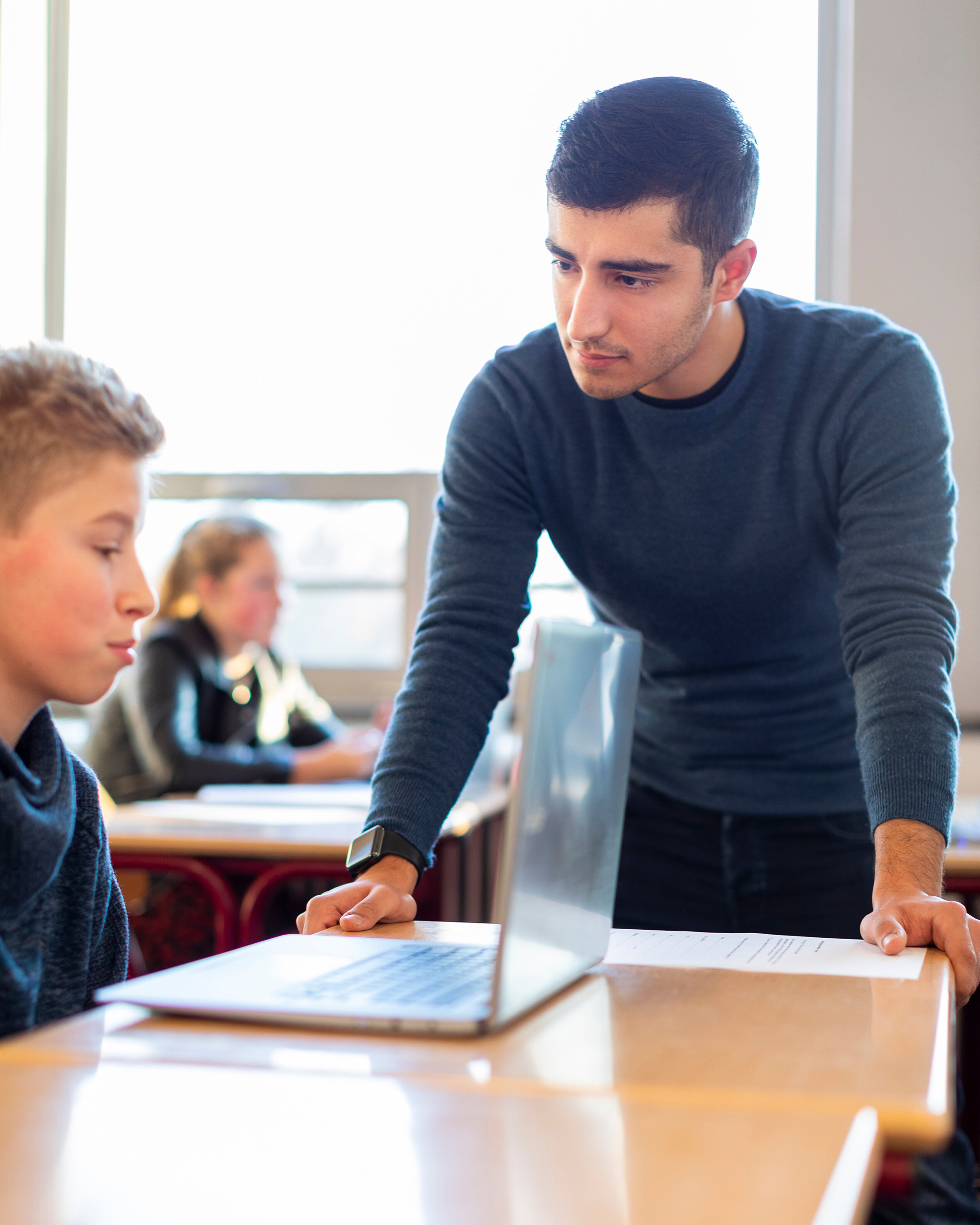 Deeltijdstudent opleiding Leraar Frans met leerling achter de laptop in de klas. 