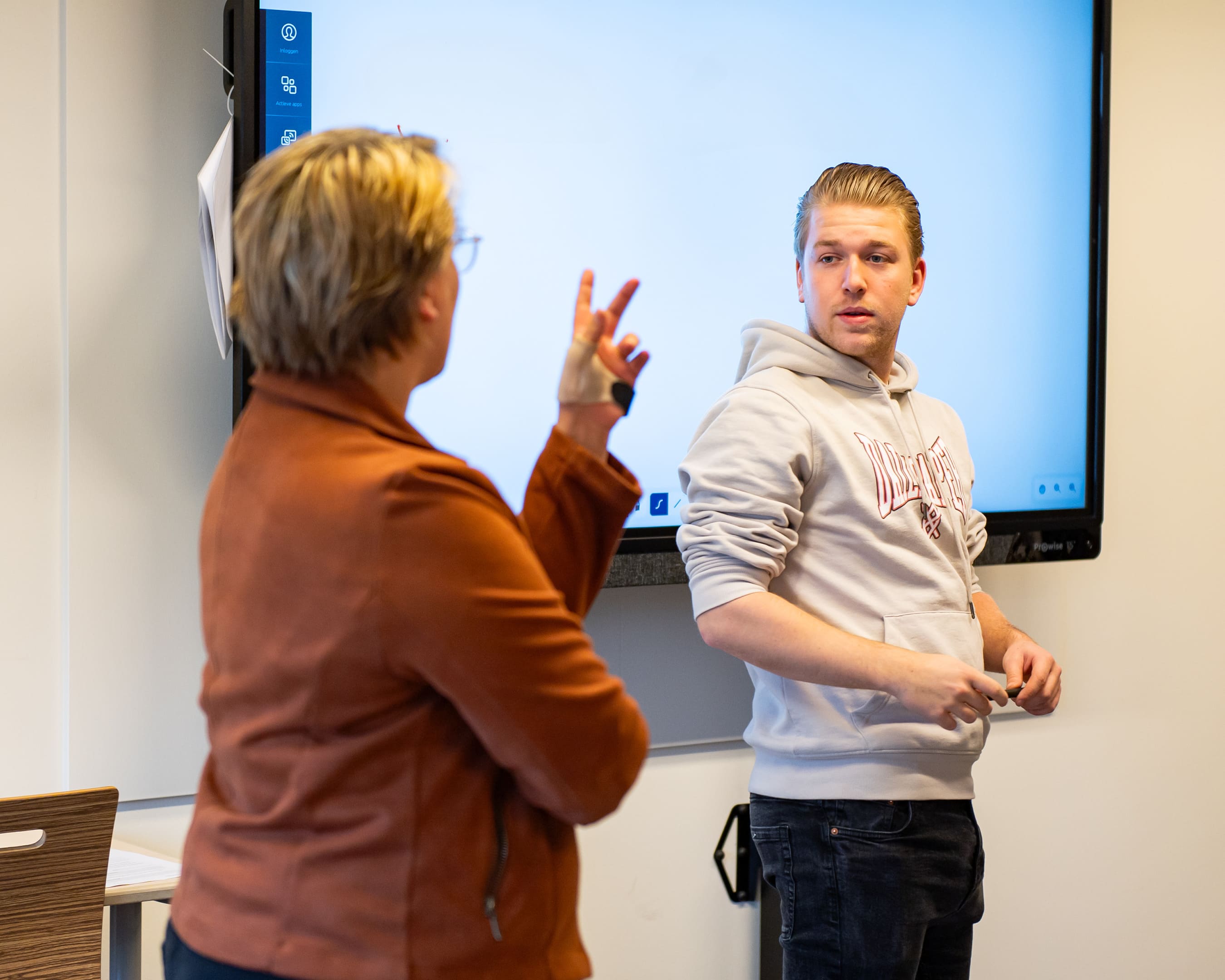 Docent met student in gesprek voor digibord