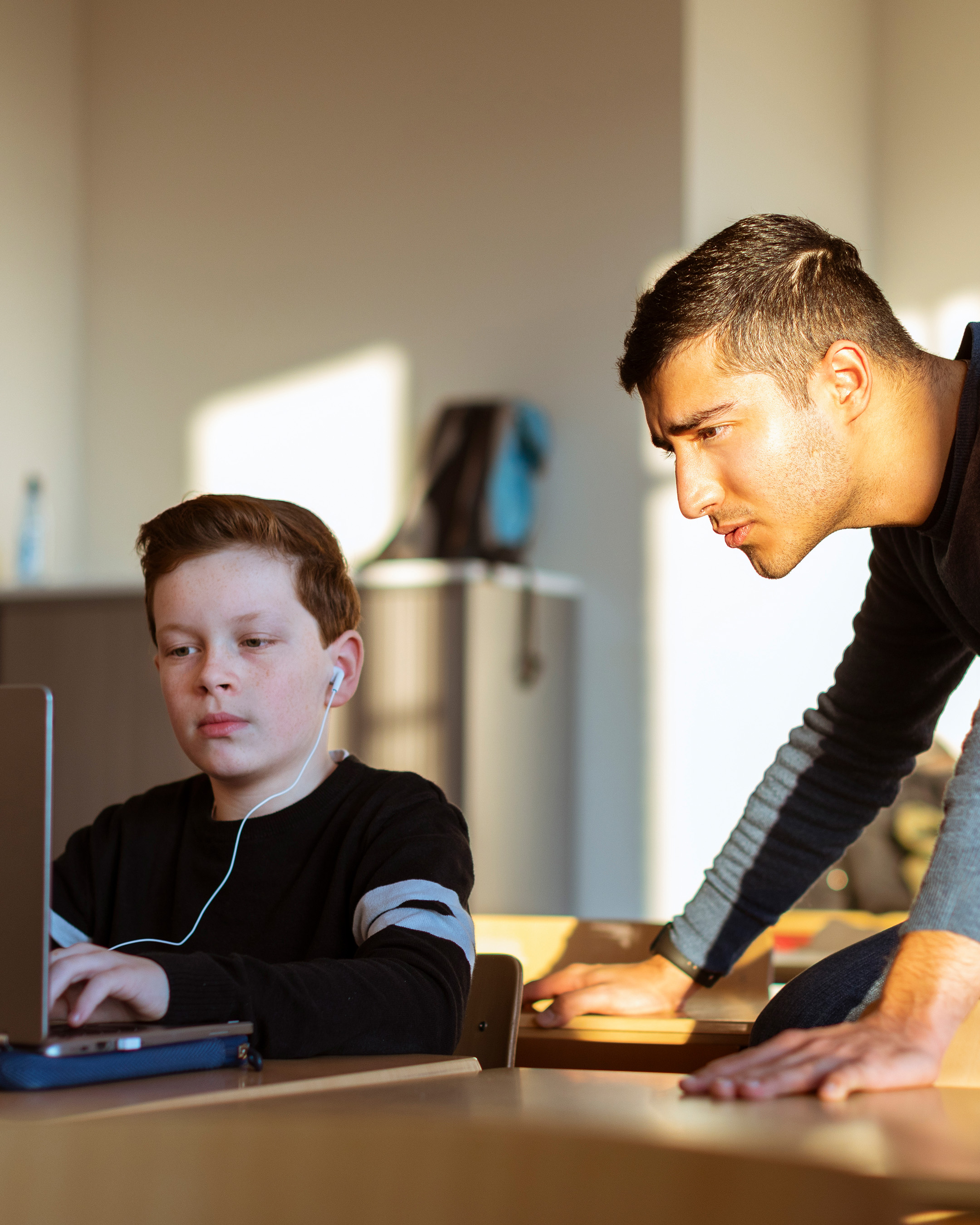 Student deeltijdlerarenopleiding Spaans met leerling achter laptop