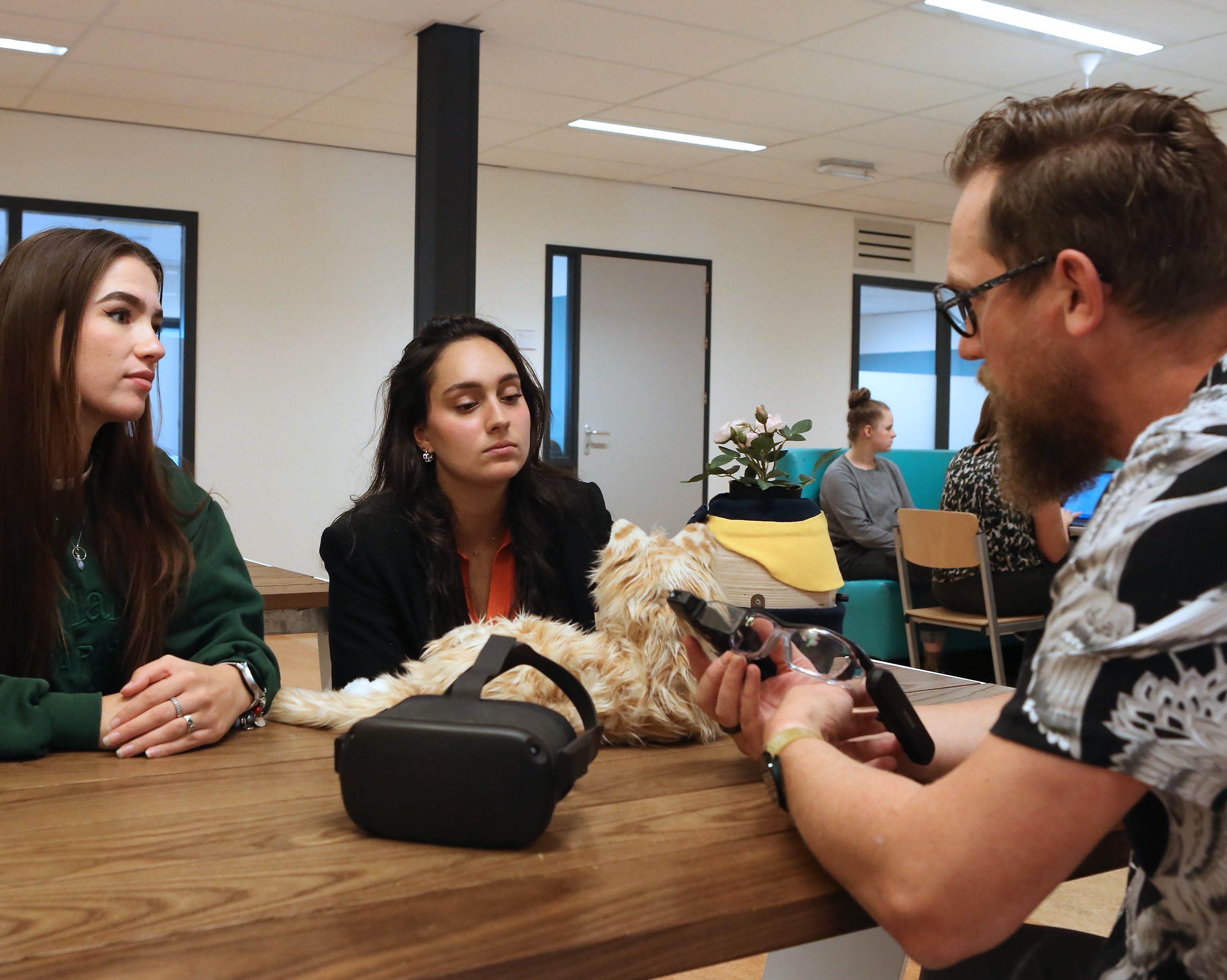 Studenten van Zorg en Technologie bespreken hulpmiddelen, waaronder een robotdier en een VR-bril.