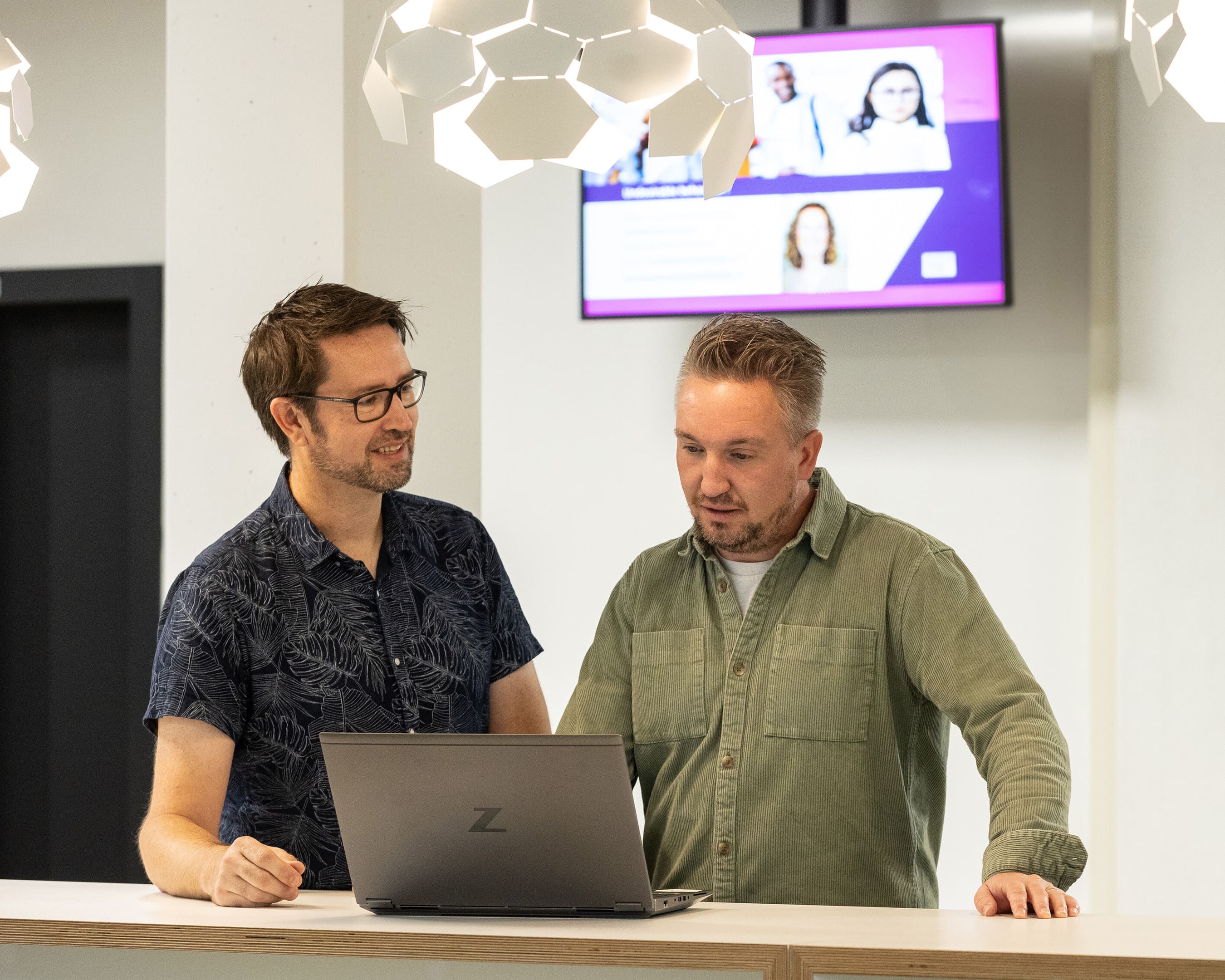 Twee studenten Ad Engineering overleggen bij een laptop.