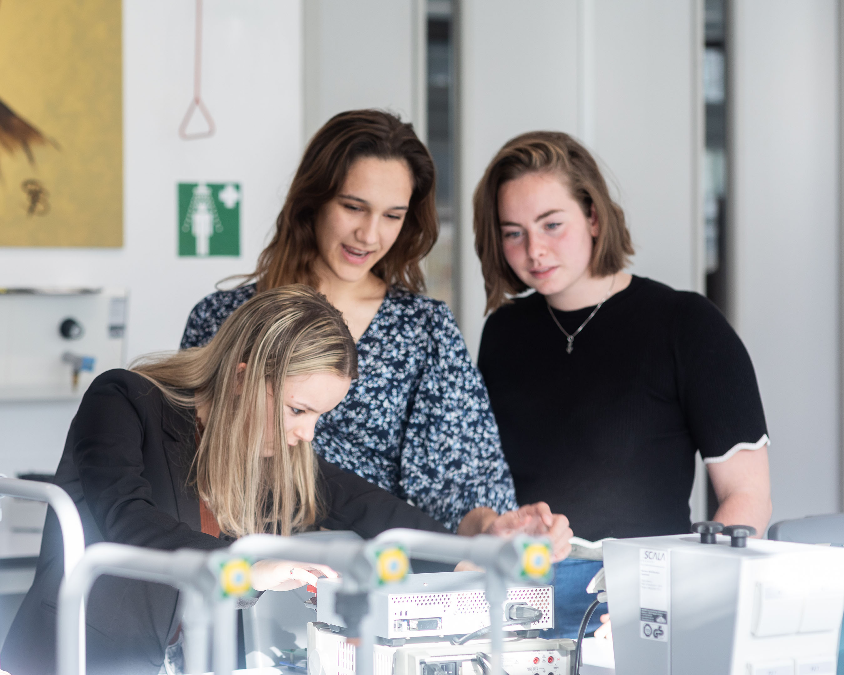 Drie studenten Technische Natuurkunde werken samen aan apparatuur