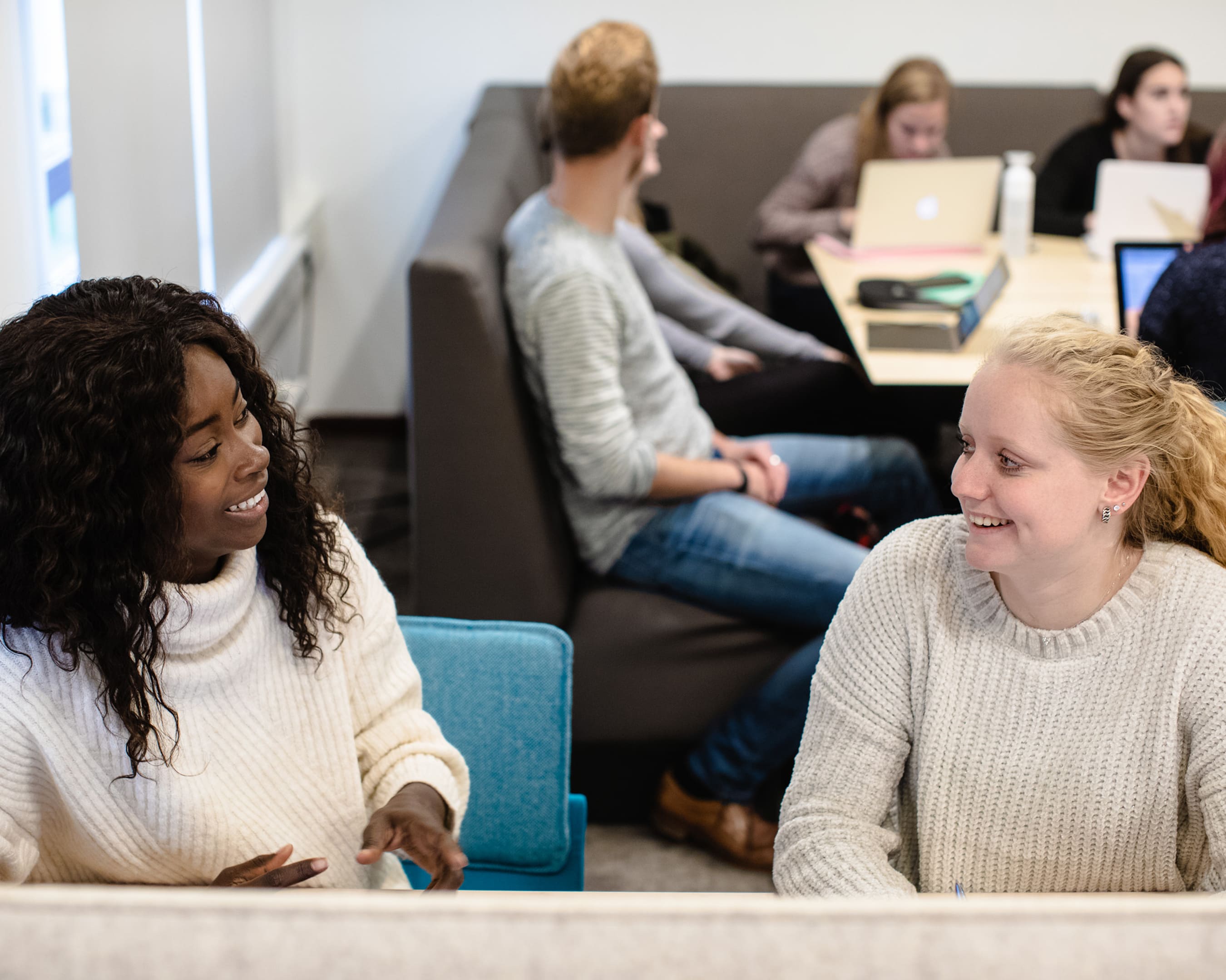 Student van de opleiding zit aan tafel met andere studenten