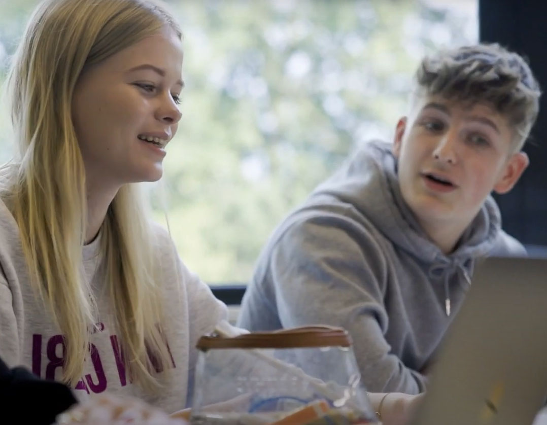 Twee studenten werken samen achter een laptop