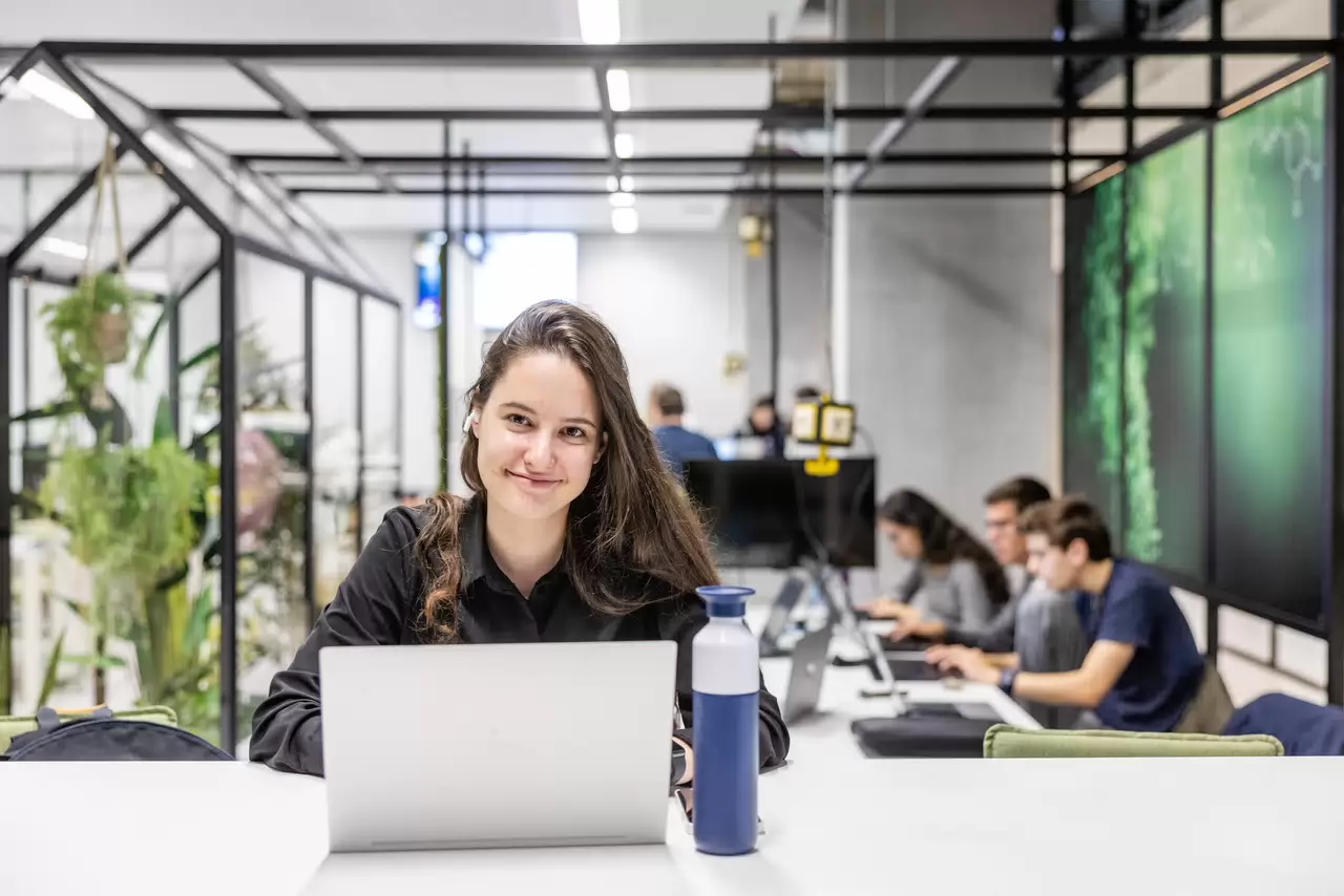 Studente met laptop voor zich, kijkt naar camera