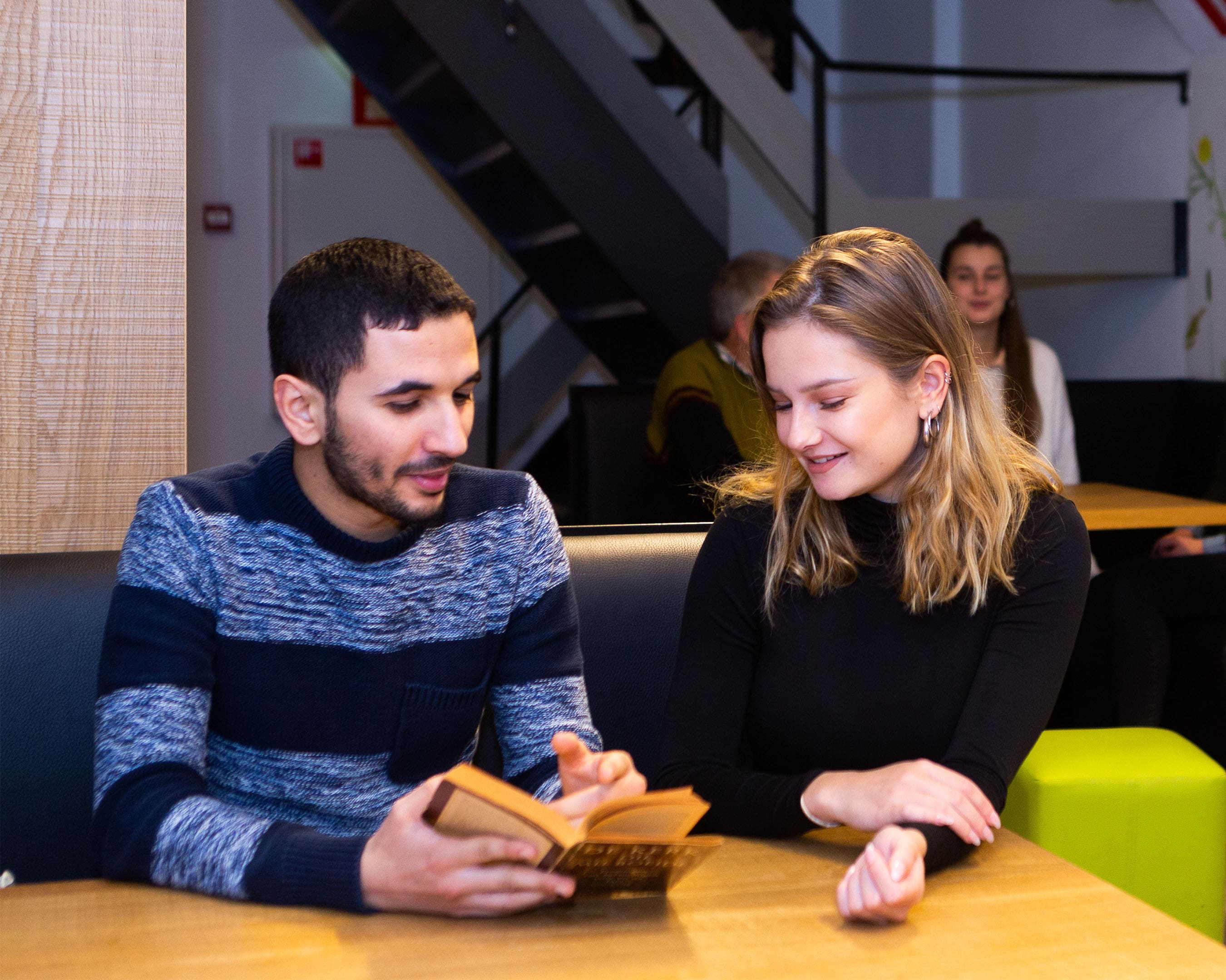 student van deeltijdopleiding Theologie legt wat uit aan een andere student