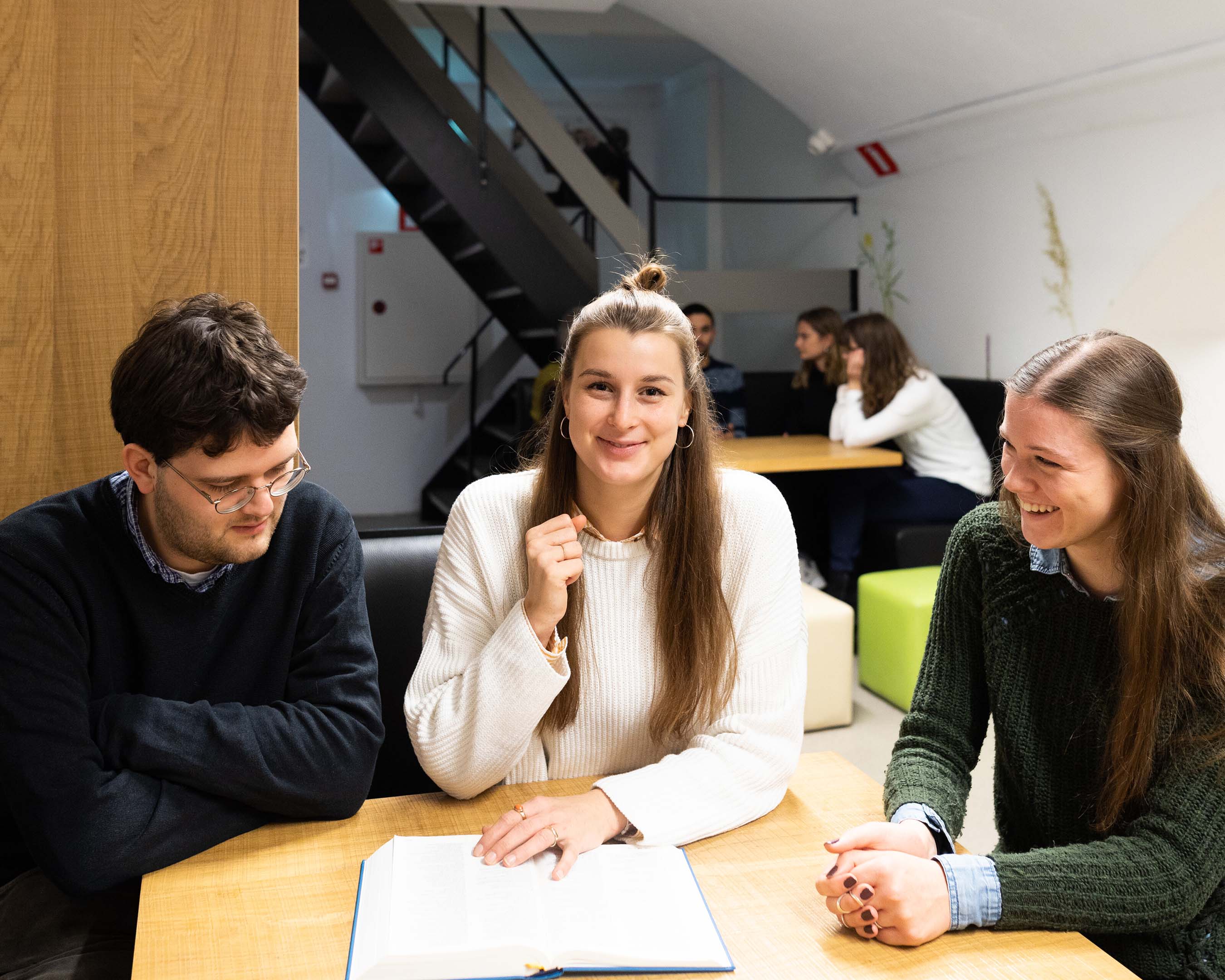 Foto van drie studenten Theologie die aan een opdracht werken