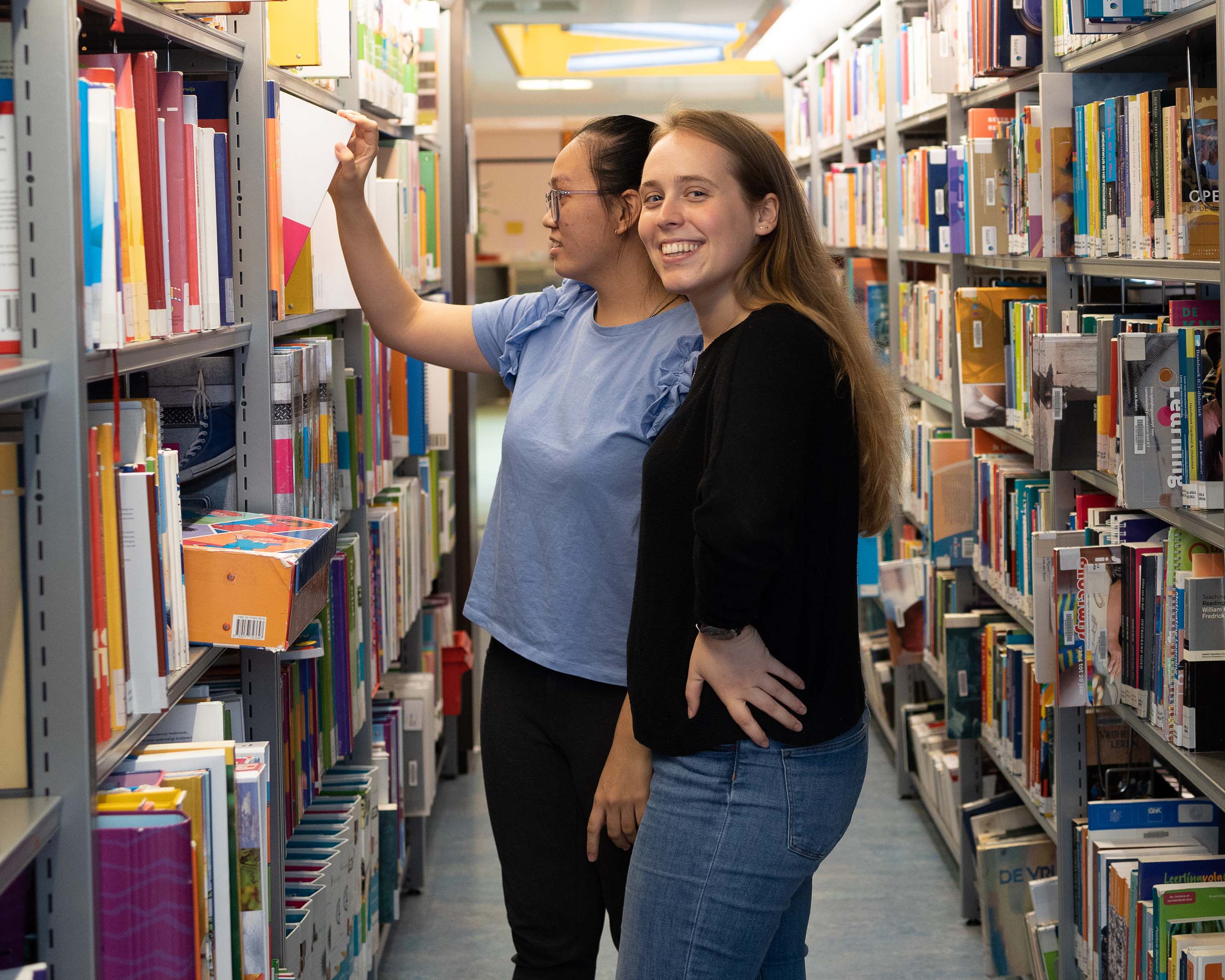 Studenten Leraar Nederlands in de bibliotheek op zoek naar literatuur