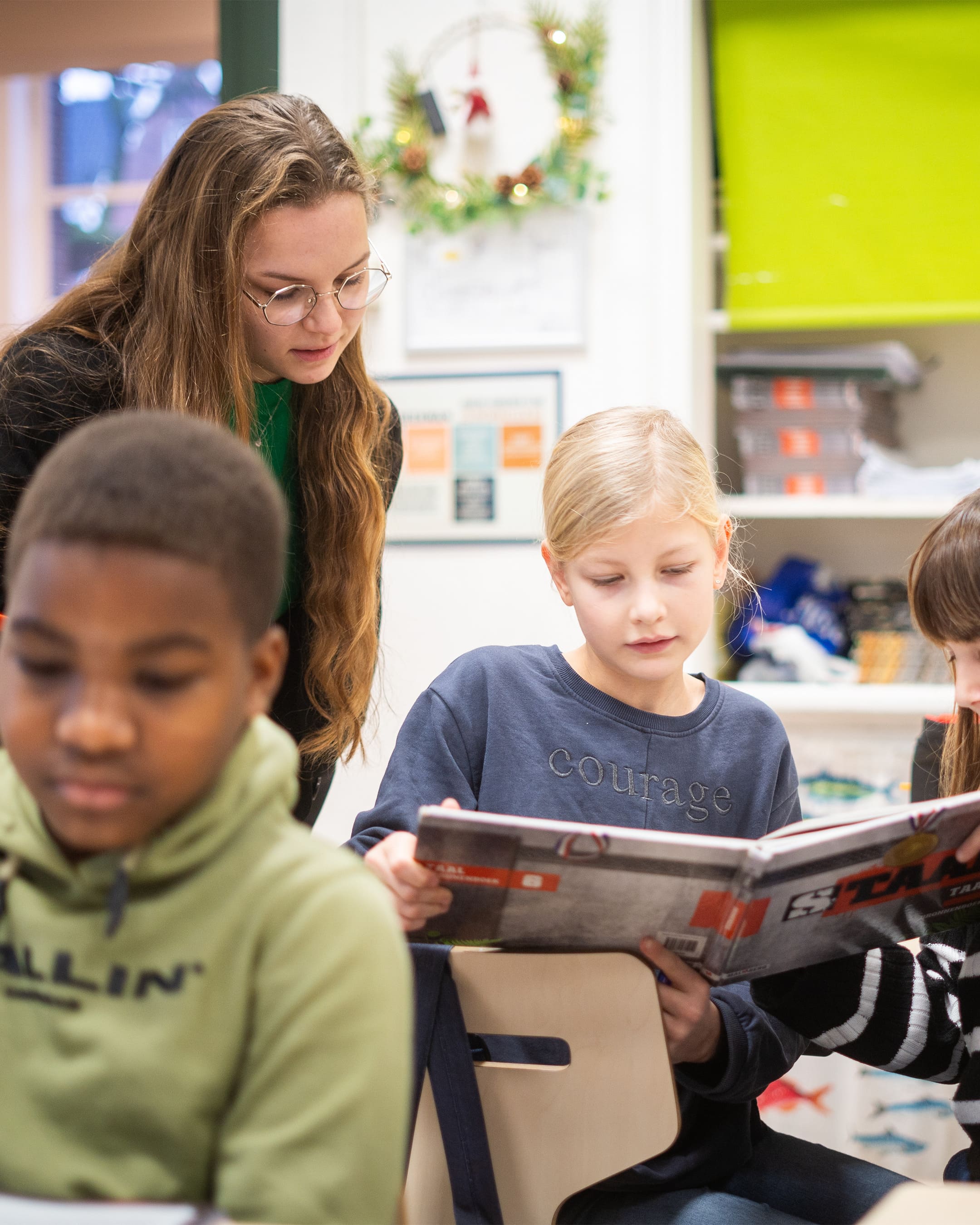 een jonge docent leest mee met een leering die in een boek kijkt