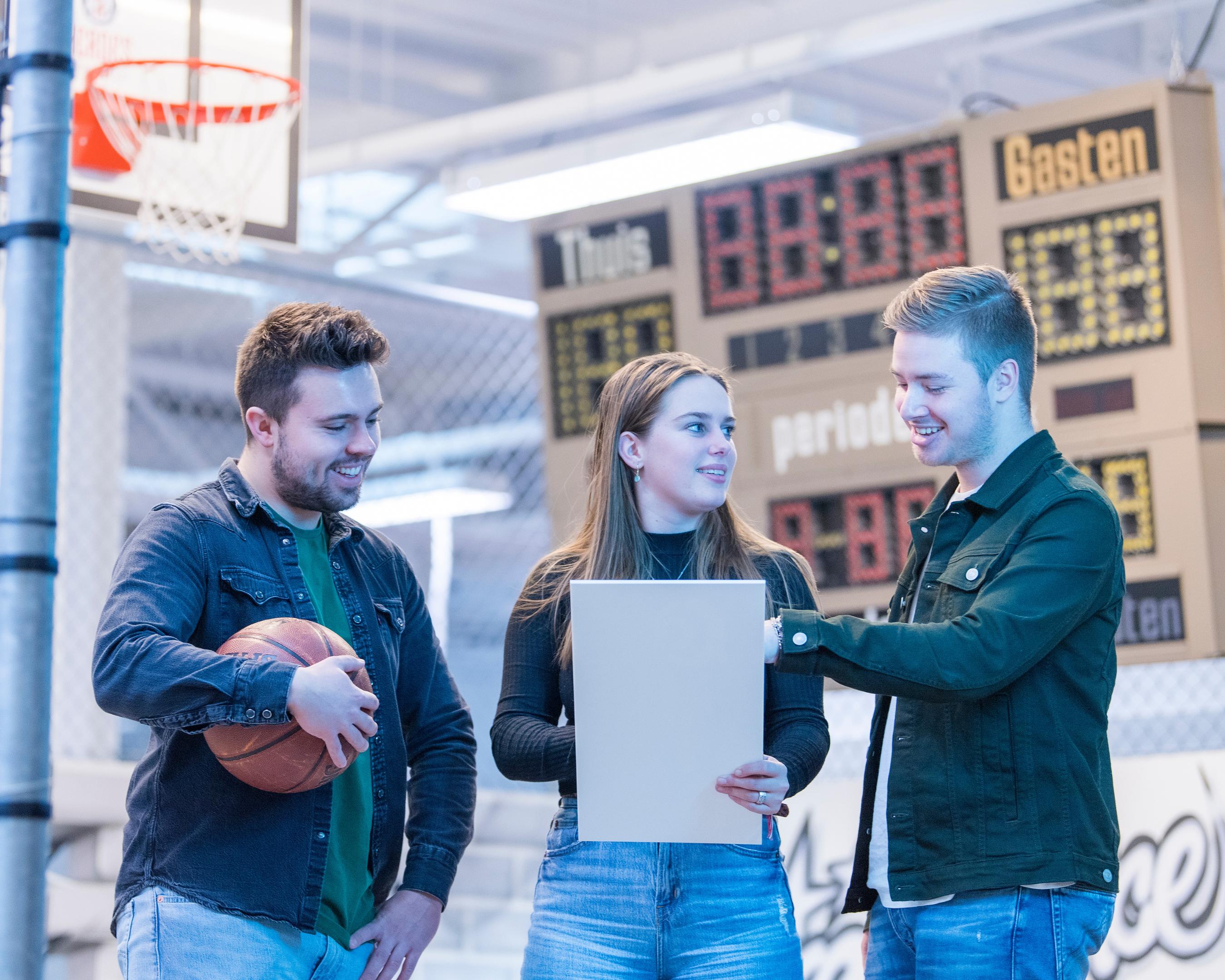 Drie studenten overleggen in een sportzaal