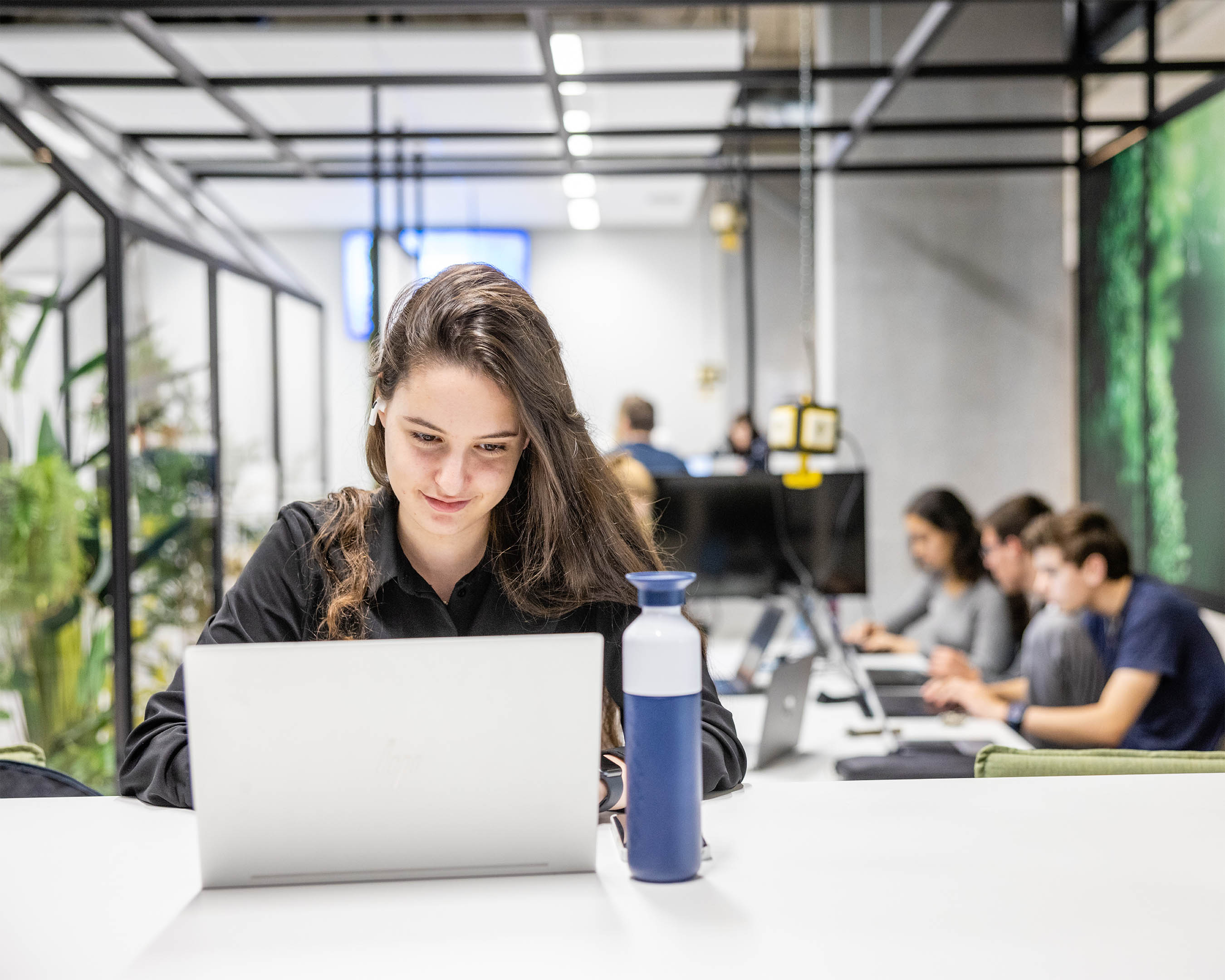 Student achter laptop met andere studenten op de achtergrond