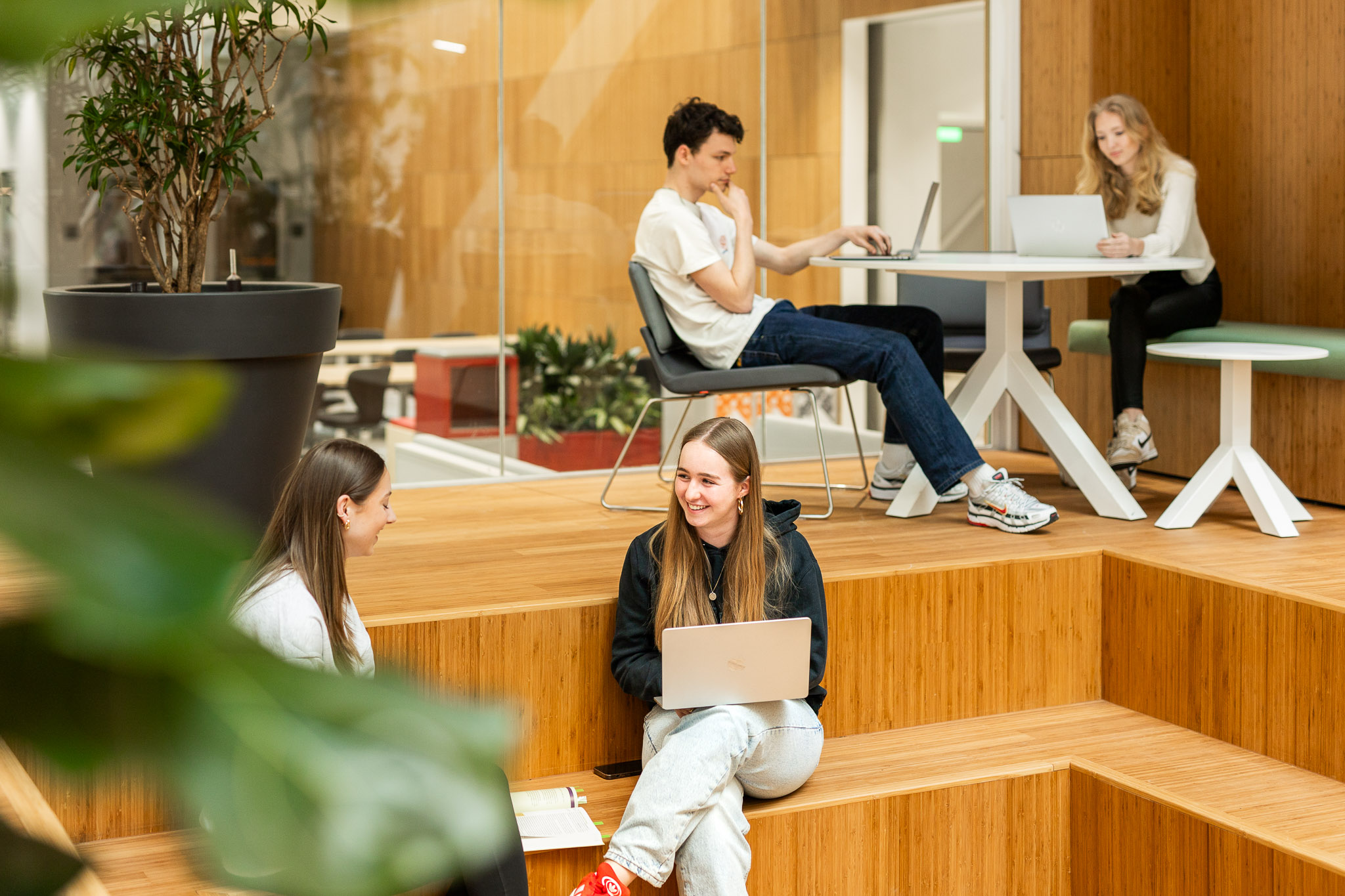 Studenten van de opleiding Social Work; 2 op de trap zittend en 2 aan een tafeltje._image_2