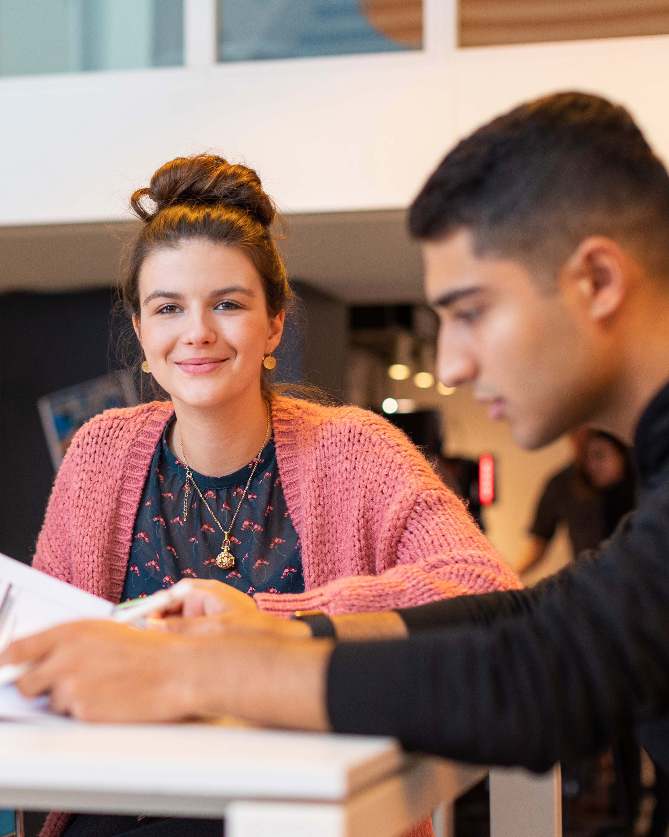 Studente Lerarenopleiding Frans werkt aan tafel met andere studenten