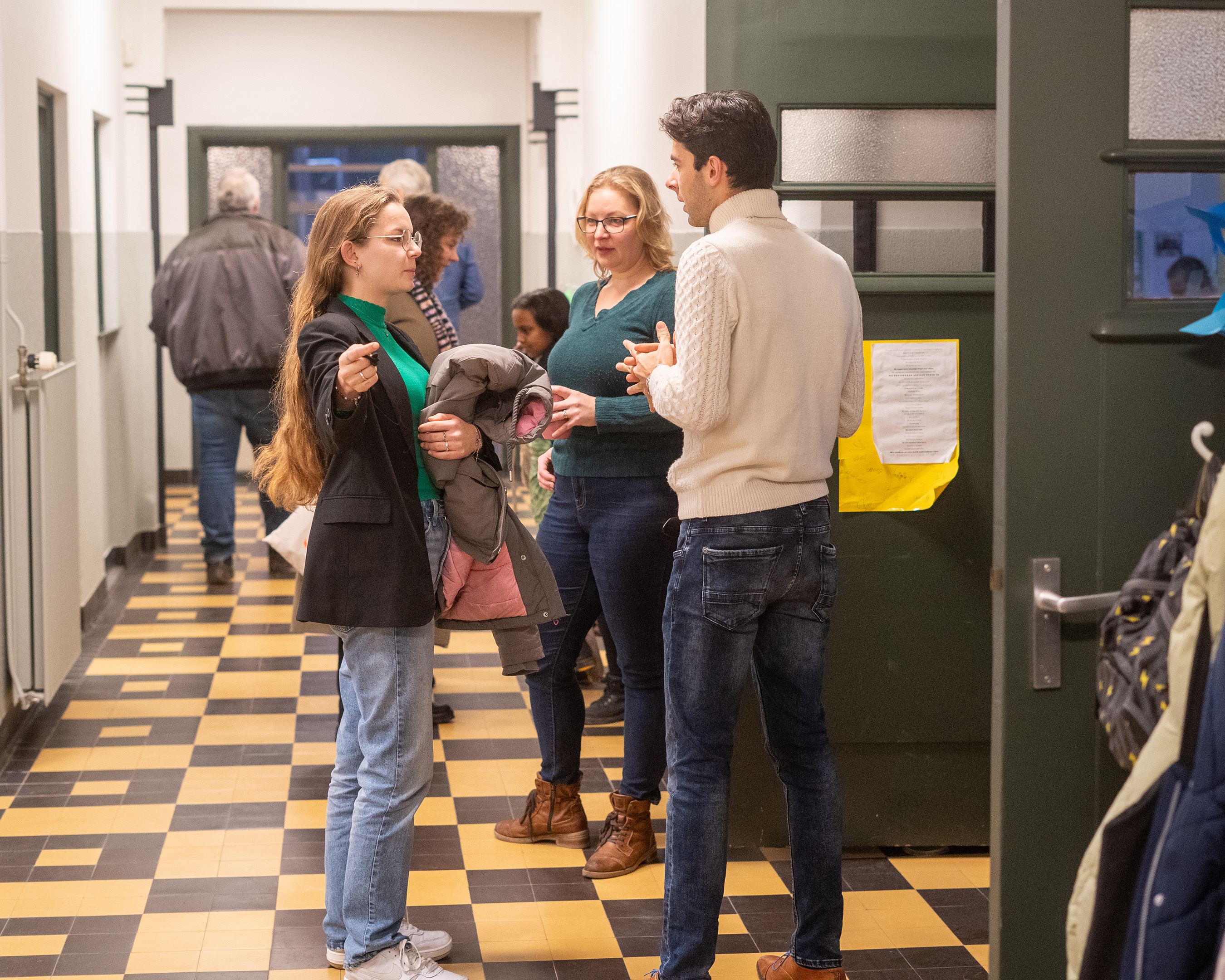 Docent met leerlingen in overleg op de gang