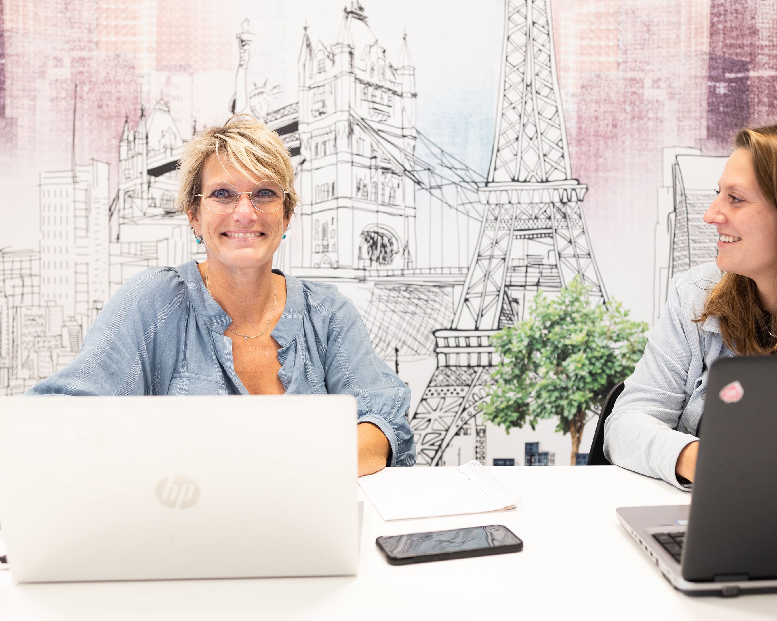 Two MBA students working on laptops at a desk.