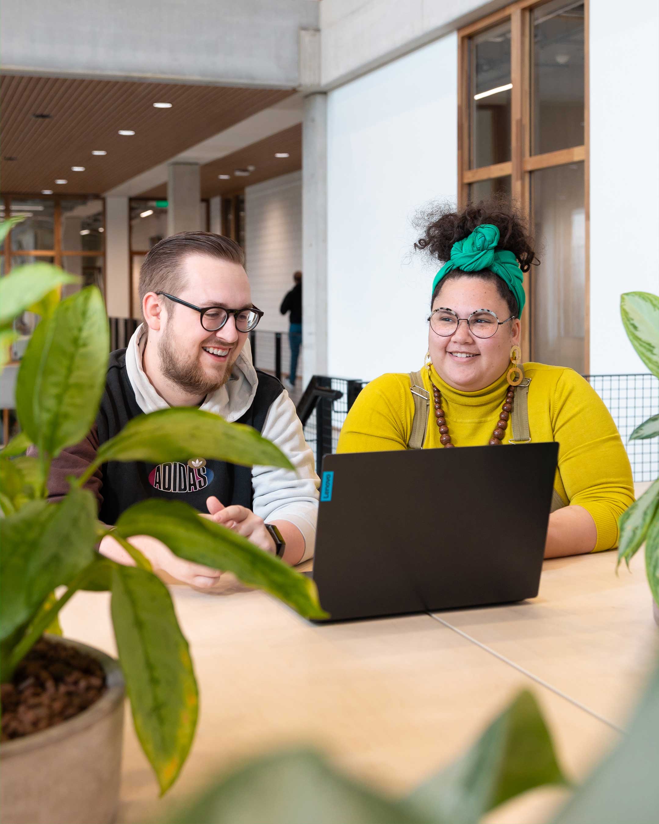 Two students Associate degree ICT work together behind a laptop.