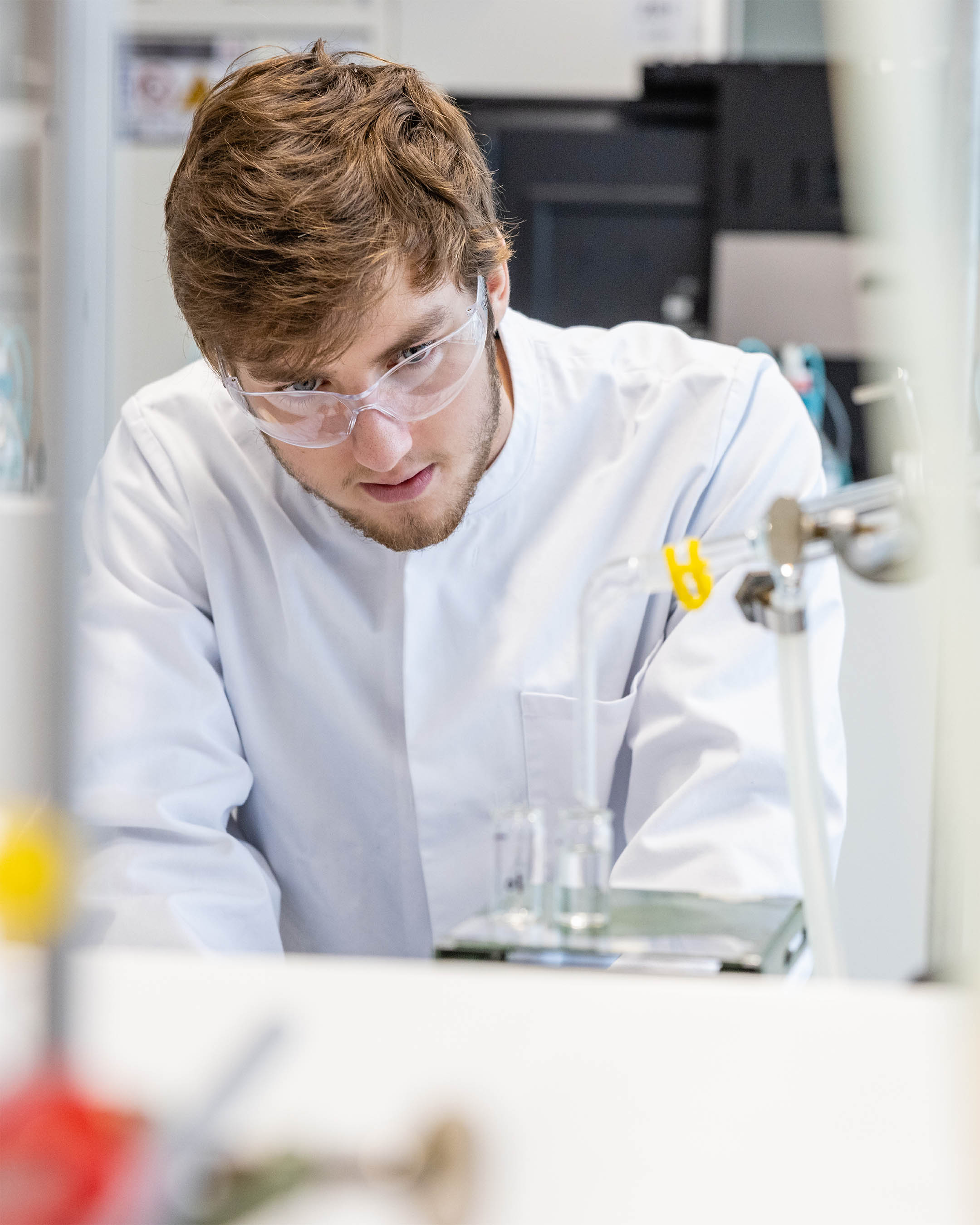 Student in witte labjas doet een proefje