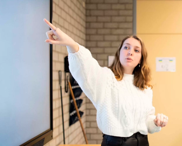 Close up van een student die bezig is met maatbekers in een practicum lokaal