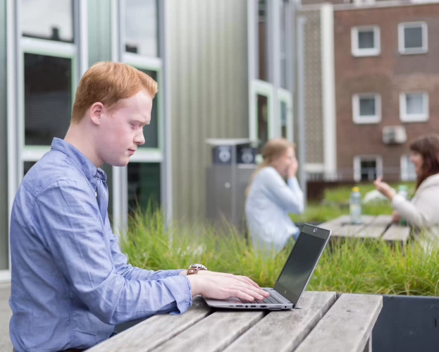 Deeltijdstudent van de opleiding Leraar Biologie werkt buiten op zijn laptop