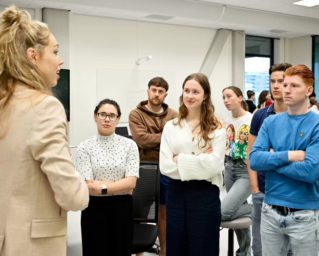 Studenten Fysiotherapie luisteren aandachtig naar een docent in een klaslokaal tijdens een interactieve les.