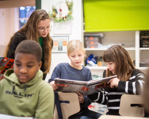 Een student Leraar Basisonderwijs geeft les aan een groep basisschoolkinderen