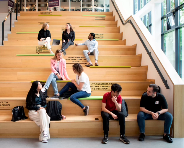 Studenten van de opleiding Finance & Control zitten binnen op de trap