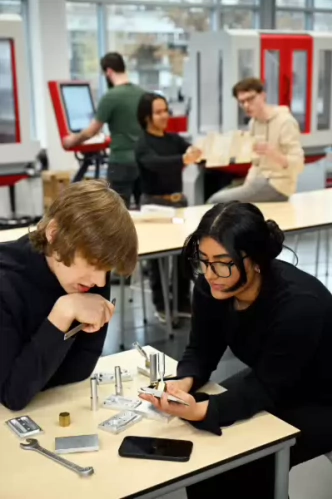 Studenten Werktuigbouwkunde werken samen aan technische onderdelen aan een tafel.