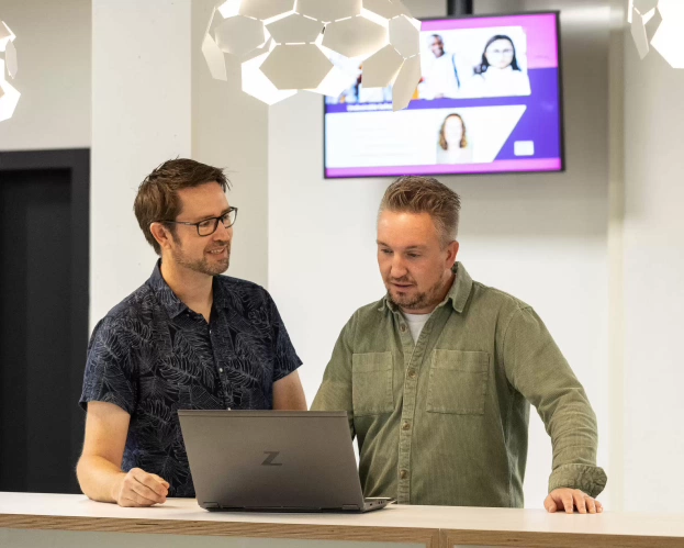 Twee studenten Ad Engineering overleggen bij een laptop.