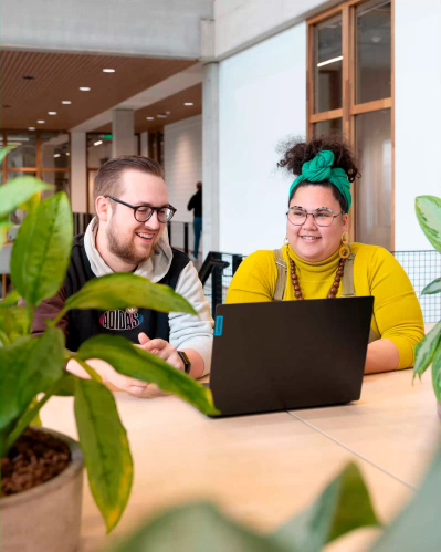 Two students Associate degree ICT work together behind a laptop.