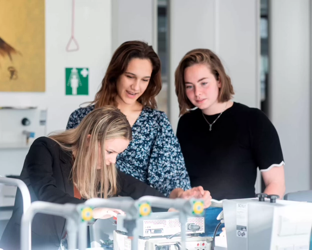 Drie studenten Technische Natuurkunde werken samen aan apparatuur