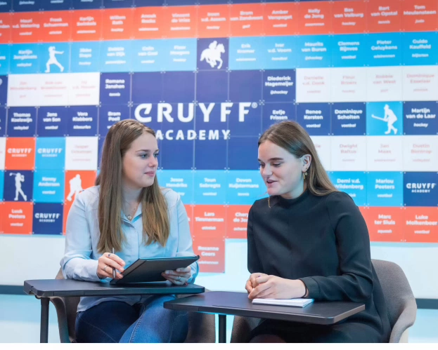 Twee studenten Johan Cruyff Academy hebben zittend naast elkaar een bespreking