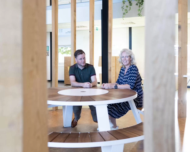 Two MBA students seated at a round wooden table in a modern space.