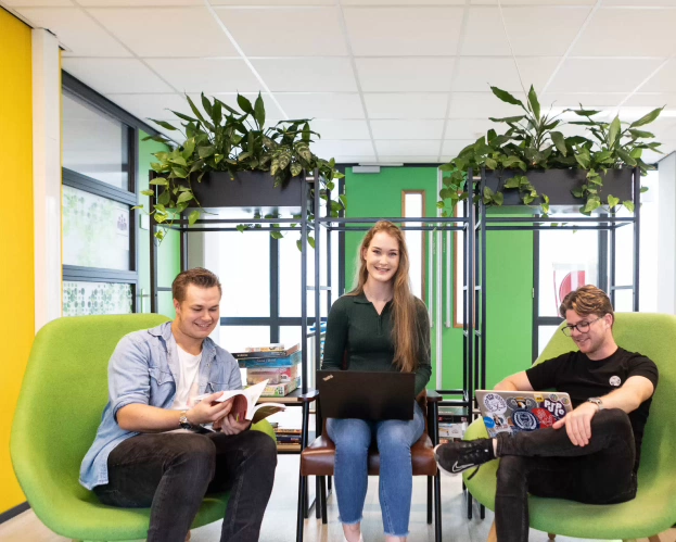 3 studenten zitten bij elkaar met een laptop en boek voor de opleiding Leraar Duits.