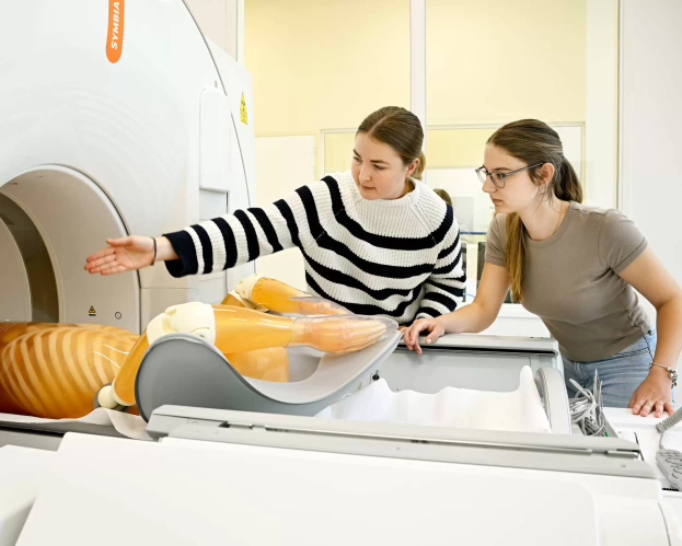 Twee studenten bij een MRI-scanner bespreken de positie van een anatomisch model.