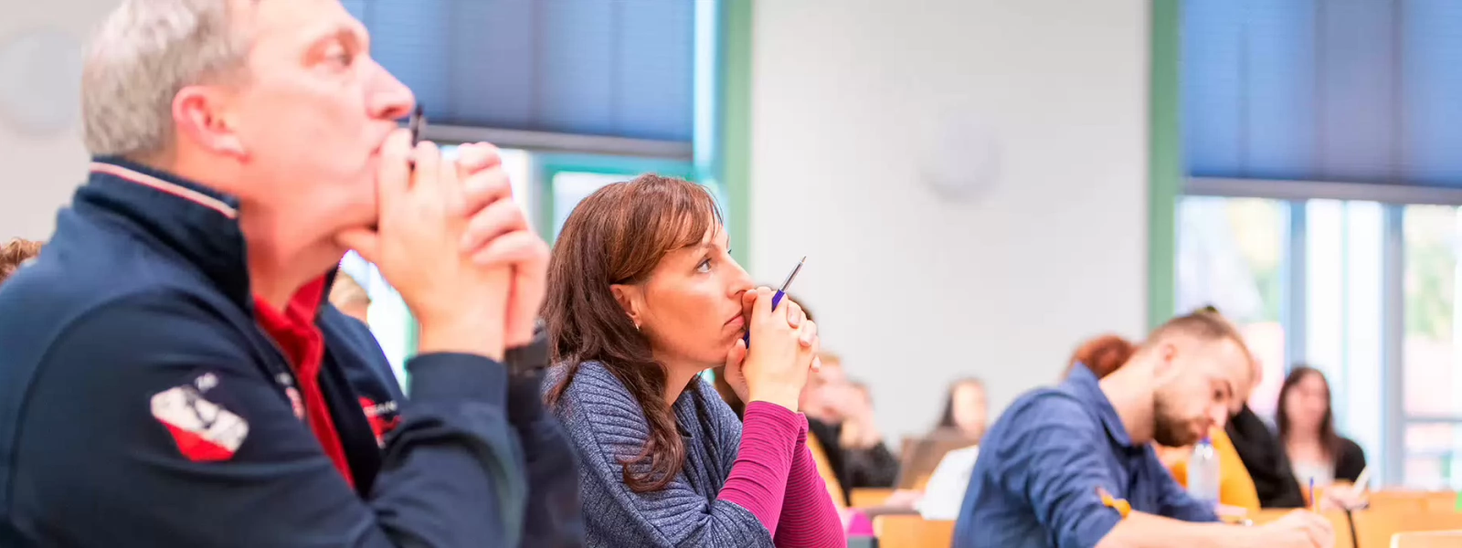 Een groep volwassen die een les volgen in een collegezaal