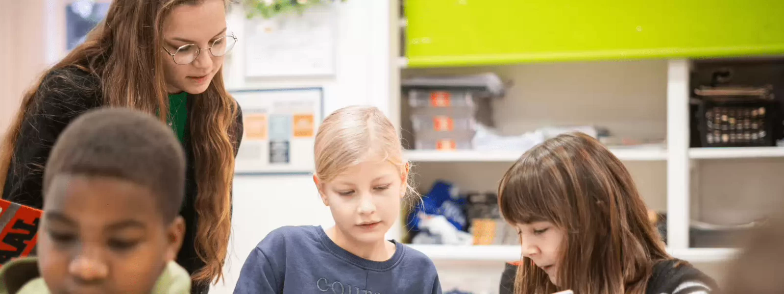 sfeerbeeld juffrouw  in de klas met lezende kinderen 