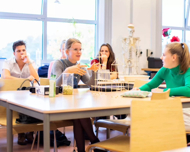 Drie verschillende studenten bespreken iets achter een laptop