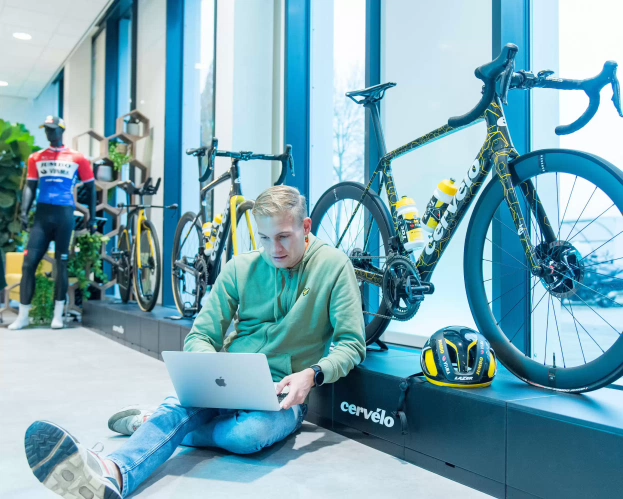 een student kijkt op laptop en zit op de grond