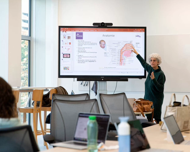 Docent van de opleiding Verpleegkunde legt in de klas wat uit.