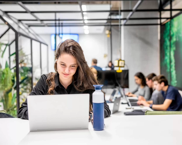 Student achter laptop met andere studenten op de achtergrond