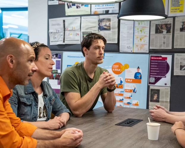 Docent en studenten aan tafel met elkaar in gesprek voor opleiding Leraar Techniek