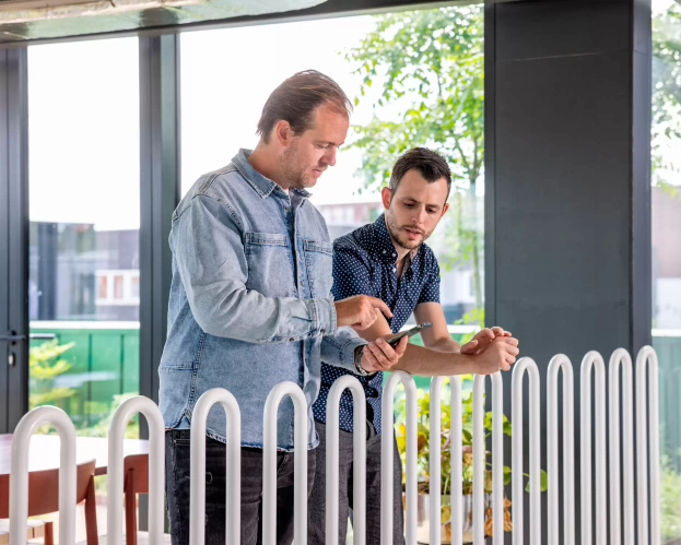 Student en docent kijken samen naar een telefoon