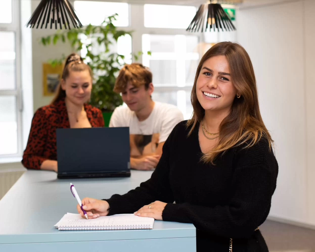 Meisje kijkend naar camera met werkende studenten achter haar